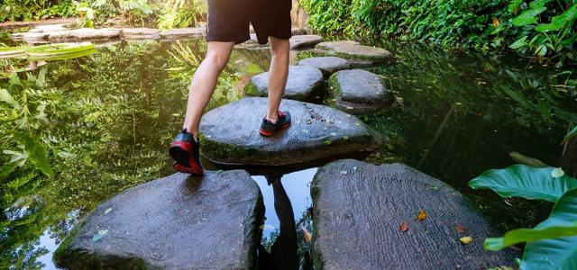 A person walking on stone steps on an outdoor pond.